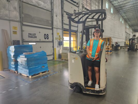 Young man standing on a forklift