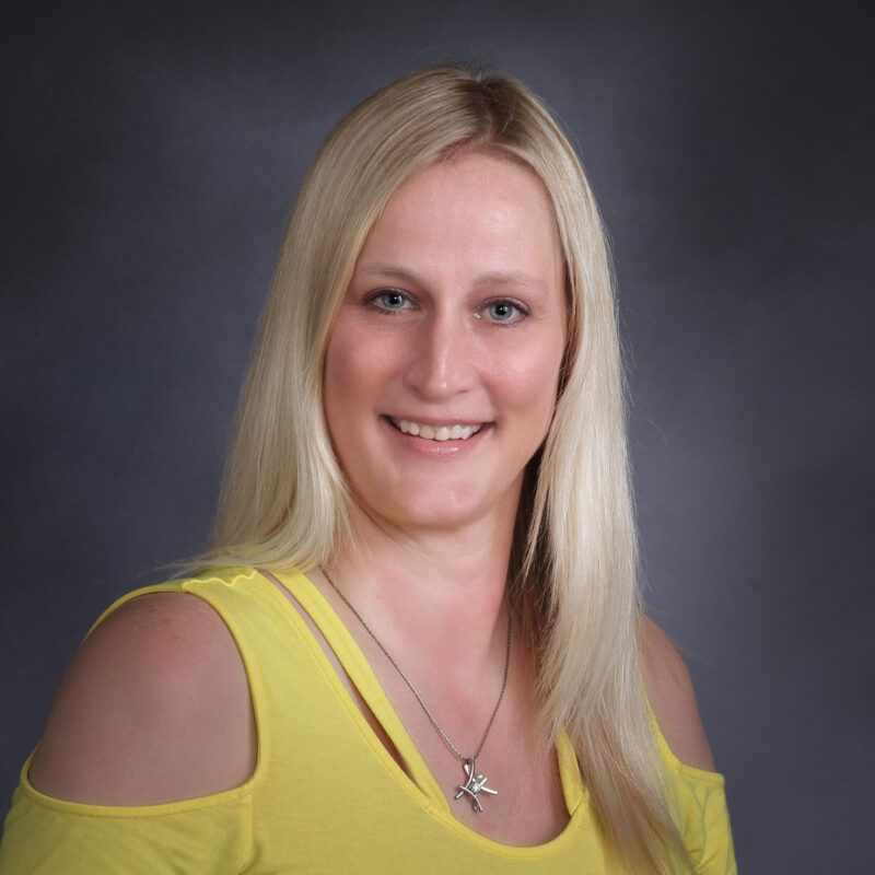 Photo of Diana Barber, a woman with long blonde hair wearing a yellow shirt