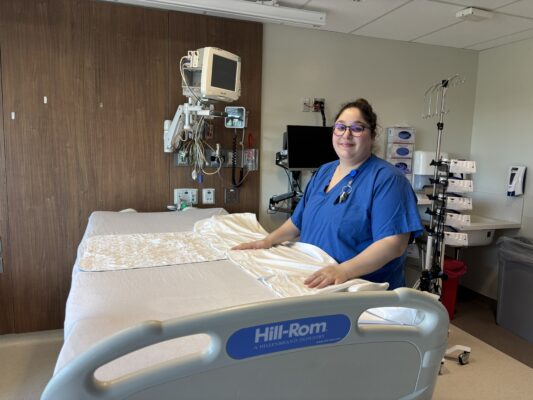A young woman with a disability changing bed sheets in her job at BJC HealthCare which she trained for at the BCI Skills Center